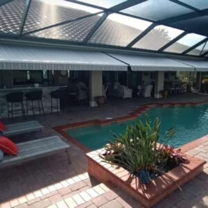 Three retractable awnings installed inside a screened pool enclosure, providing shade over a patio and pool area.